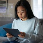 Mujer preocupada revisando su tablet con gráficos de inteligencia artificial en pantalla, destacando la importancia de proteger la privacidad al usar IA.