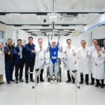 Equipo médico y científicos de la Universidad de Fudan posan con un paciente en proceso de rehabilitación asistida por un sistema de interfaz cerebro-columna, destacando el uso de inteligencia artificial para recuperar la movilidad.