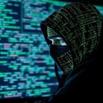 Hacker encapuchado con código binario, representando los riesgos de la inteligencia artificial en ciberseguridad.