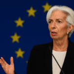 Christine Lagarde, presidenta del Banco Central Europeo, habla en una conferencia con la bandera de la Unión Europea de fondo, abordando los riesgos de frenar la inteligencia artificial en Europa.